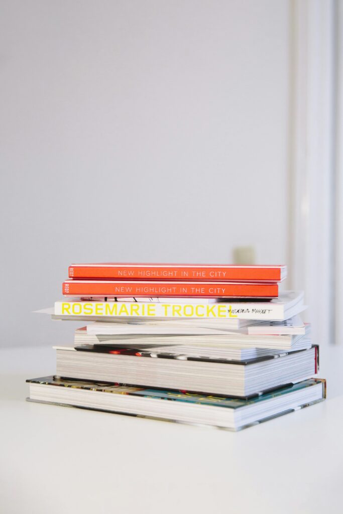 A neatly stacked pile of hardcover books on a white table.